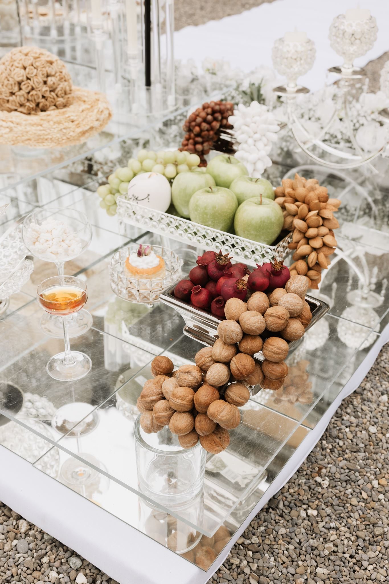 Sofreh aghd detail — walnuts, pomegranates, green apples and sweets arranged on a mirrored table